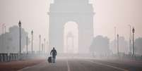 Um homem com uma mala caminha em direção ao Portão da Índia em Nova Déli envolto em poluição  Foto: Getty Images / BBC News Brasil