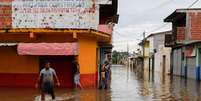 Pessoas caminham por ruas alagadas em Itajuipe, na Bahia - 27/12/2021  Foto: REUTERS/Amanda Perobelli