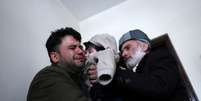 O taxista Hamid Safi, que encontrou o bebê, chora ao entregá-lo ao avô  Foto: Ali Khara / Reuters