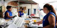 Três mulheres negras usam coletes azuis e estão catando recicláveis  Foto:  Elizabeth Nader/Prefeitura de Vitória / Alma Preta