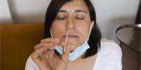 Mulher branca insere coletor de amostra em seu próprio nariz  Foto: Getty Images / BBC News Brasil