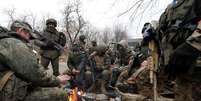 Membros do servi&ccedil;o de tropas pr&oacute;-R&uacute;ssia em uniformes sem ins&iacute;gnias se re&uacute;nem em torno de uma fogueira no assentamento controlado pelos separatistas de Mykolaivka (Nikolaevka), enquanto a R&uacute;ssia continua ofensiva contra a Ucr&acirc;nia  Foto: REUTERS/Alexander Ermochenko 