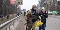 Militar ucraniano ajuda mulher a fugir de região sob ataque russo; símbolo adicionado por ele ao uniforme chamou a atenção nas redes sociais por ser associado ao nazismo  Foto: Anastasia Vlasova/Getty Images / BBC News Brasil