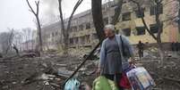 Uma mulher caminha do lado de fora de uma maternidade atingida por um bombardeio russo em Mariupol, Ucrânia  Foto: Evgeniy Maloletka