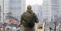 Soldado com metralhadora perto do centro comercial destru&iacute;do de Retroville ap&oacute;s bombardeio russo  Foto: Getty Images / BBC News Brasil