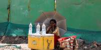 Garota vende água debaixo de guarda-sol em meio ao forte calor em Nova Délhi 27/04/2022  Foto: REUTERS/Anushree Fadnavis