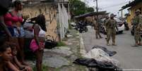 Moradores e policiais ao lado de um corpo coberto após operação policial que deixou 23 mortos na Vila Cruzeiro, Rio de Janeiro  Foto: DW / Deutsche Welle