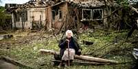 Uma mulher se senta em frente a duas casas que foram demolidas por um ataque de míssil, que matou outra mulher, em Druzhkivka, Donetsk  Foto: Getty Images / BBC News Brasil