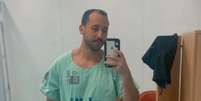 Giovanni está na frente de um espelho. Ele segura um celular e usa um uniforme de hospital  Foto: Reprodução/Redes sociais / Alma Preta