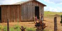 Foto de uma casa quilombola da comunidade Paiol de Telha. Na porta da moradia, estão duas crianças.  Foto: Imagem: Lizely Borges/Terra de Direitos / Alma Preta