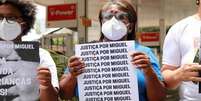 Mulher negra segura cartaz em que se lê: Justiça por Miguel.  Foto: Imagem: Débora Oliveira / Alma Preta Jornalismo / Alma Preta