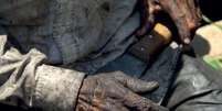 Imagem mostra mãos de um homem negro que segura um facão  Foto: Divulgação/ASCOM MTE / Alma Preta