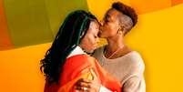Imagem mostra duas mulheres negras envolvidas na bandeira da comunidade LGBT. Uma beija a testa da outra.  Foto: Imagem: Reprodução/Sinasefe / Alma Preta