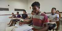 Estudantes pretos estão sentados em cadeiras escolares para retratar a Lei de Cotas  Foto: Marcello Casal Jr/Agência Brasil / Alma Preta