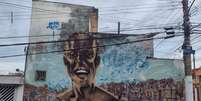 Grafite do grupo OPINI, na Rua Vitório Azzalin, em São Mateus, traz Tia Cida alegre sobre as favelas do bairro @Matheus Oliveira/Agência Mural  Foto: Agência Mural