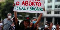 A imagem mostra uma manifestante segurando o cartaz escrito: não sou mãe e defendo o aborta legal e seguro  Foto: Imagem: Pilar Olivares/Reuters / Alma Preta