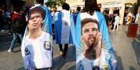 Torcedores argentinos carregam bandeiras com imagens dos ídolos Diego Maradona e Lionel Messi na terça-feira, 13, no Catar.  Foto: Bernadett Szabo / Reuters