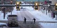 Dois homens atravessam uma rua coberta de neve em Denver, Colorado, em meio a uma forte tempestade de inverno em 22 de dezembro de 2022  Foto: Getty Images / BBC News Brasil