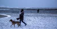 Mulher anda com o cachorro em Lake Ontario, no Canadá  Foto: Reuters / BBC News Brasil