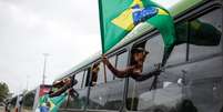 ônibus com apoiadores de Bolsonaro e bandeira do Brasil  Foto: Reuters / BBC News Brasil