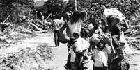 Famílias levando pertences após chuvas fortes atingirem o município de Caraguatatuba, em 1967  Foto: Arquivo Municipal de Caraguatatuba / BBC News Brasil