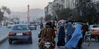 Mulheres de burca atravessam rua em frente a membros do Taliban em Cabul, no Afeganist&atilde;o  Foto: Reuters