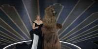 Elizabeth Banks e o urso de Cocaine Bear no palco do Oscar   Foto: Carlos Barria
