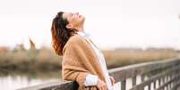 Mulher feliz com o rosto virado para o Sol sobre uma ponte  Foto: Getty Images / BBC News Brasil