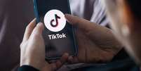 Pessoa de costas usando celular, que mostra logo do TikTok  Foto: Getty Images / BBC News Brasil