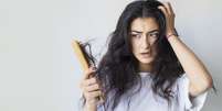 Mulher assustada com cabelo na escova  Foto: Hazal Ak / iStock