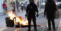 Policiais olham incêndio na rua  Foto: Getty Images / BBC News Brasil