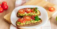 P&atilde;o torrado com pasta de abacate e tomate fresco  Foto: iStock