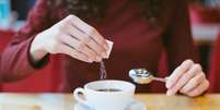 Mulher usa adoçante no café; aspartame foi classificado como potencialmente cancerígeno  Foto: iStock