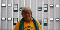 Imagem mostra Regina L&uacute;cia dos Santos. Ela &eacute; uma idosa negra de pele clara, com cabelos grisalhos curtos e veste uma camiseta amarela, escrito Movimento Negro Unificado.  Foto: Reprodu&ccedil;&atilde;o/Brasil de Direitos / Alma Preta