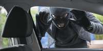 Ladrão encapuzado olhando através da janela de um carro  Foto: Getty Images / BBC News Brasil