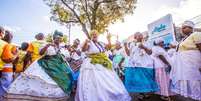 A imagem mostra um grupo de mulheres com trajes típicos da Bahia em celebração na via pública.  Foto: Alma Preta