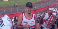 Imagem mostra Rafael Garcia nas arquibancadas do estádio Cícero Pompeu de Toledo rodeado de torcedores do São Paulo. O jovem usa boné preto, óculos de grau e uma camisa do time de futebol.  Foto: Alma Preta