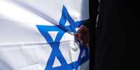 Uma pessoa segura a bandeira de Israel em ato pela paz, ap&oacute;s guerrilheiros do Hamas invadirem territ&oacute;rio israelense  Foto: REUTERS/Kacper Pempel