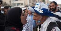 Uma mulher muçulmana e um homem com a bandeira de Israel na bochecha discutem frente a frente   Foto: Getty Images / BBC News Brasil