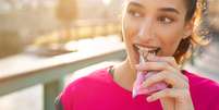 Imagem meramente ilustrativa de uma mulher comendo uma barrinha de cereal  Foto: Ridofranz / iStock