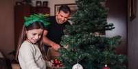 Pai e filha montam árvore de Natal; momento da montagem costuma ser uma tradição familiar  Foto: iStock