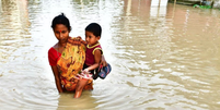 Família tenta escapar de enchente na Índia; fundo de perdas e danos coloca em questão participação do país e da China  Foto: Getty Images / BBC News Brasil