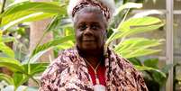 Imagem mostra Concei&ccedil;&atilde;o Evaristo, idosa negra retinta e de cabelos grisalhos. Ao fundo, h&aacute; uma planta grande.  Foto: Alma Preta