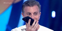 Luciano Huck atentando uma ligação ao vivo no programa Domingão com Huck.   Foto: Foto: Reprodução Globo Play