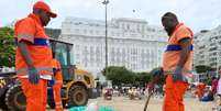 Imagem mostra dois garis negros trabalhando para retirar o lixo produzido durante as festas de fim de ano no Rio de Janeiro. Foto: Alma Preta