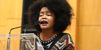 A imagem mostra a advogada quilombola Josi Santos, uma mulher negra com cabelo black power, fazendo um discurso.  Foto: Alma Preta