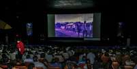 A imagem mostra uma sala de cinema cheia de pessoas assistindo a um filme.  Foto: Alma Preta