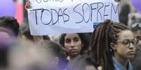 A imagem mostra uma mulher segurando um cartaz com os dizeres “ricas pagam, pobres morrem e todas sofrem” em protesto.  Foto: Alma Preta