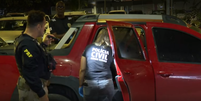 Policiais avaliam carro onde menina foi baleada  Foto: Reprodução/TV Globo