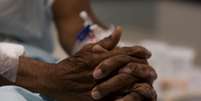 A imagem mostra as mãos de um paciente negro com acesso nos antebraços para medicação intravenosa.  Foto: Alma Preta